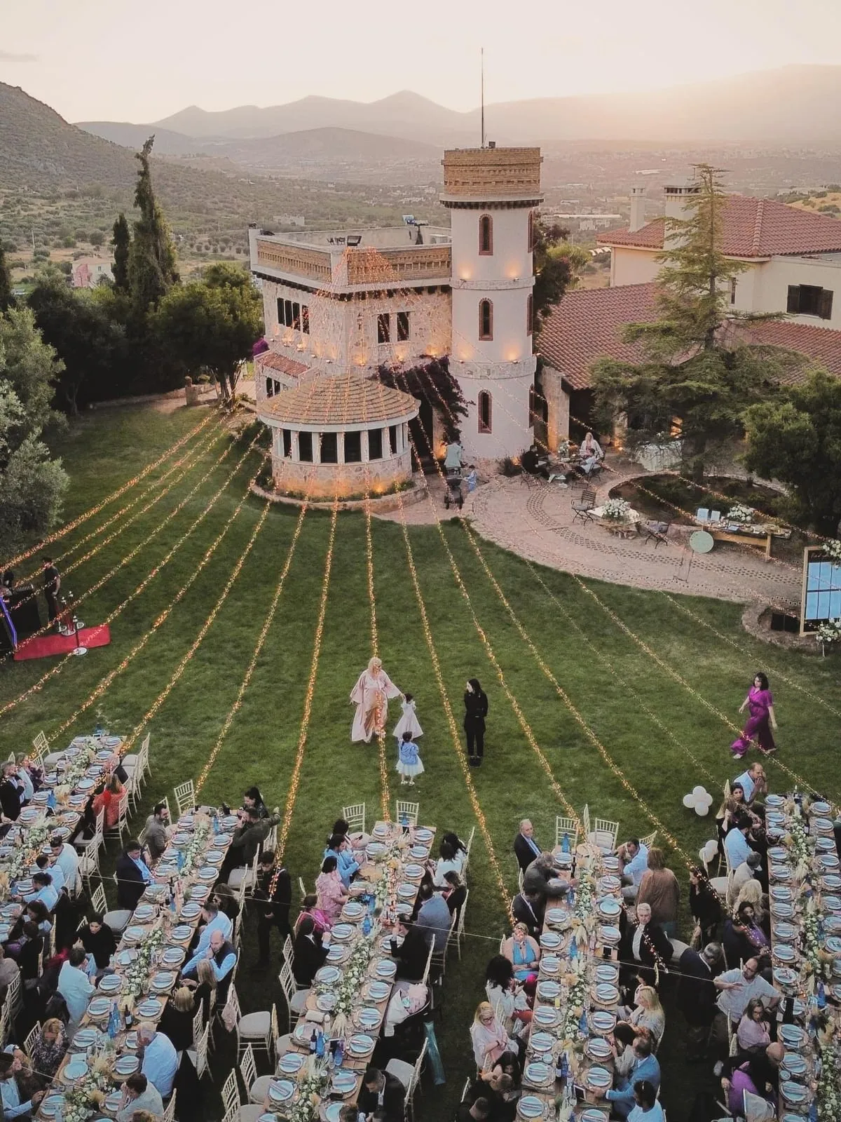 A long reception table set beneath olive trees at a Greek estate